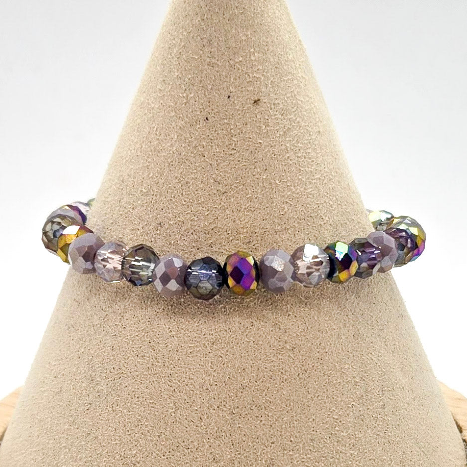 Purple beaded bracelet on a beige cone-shaped stand with a white background