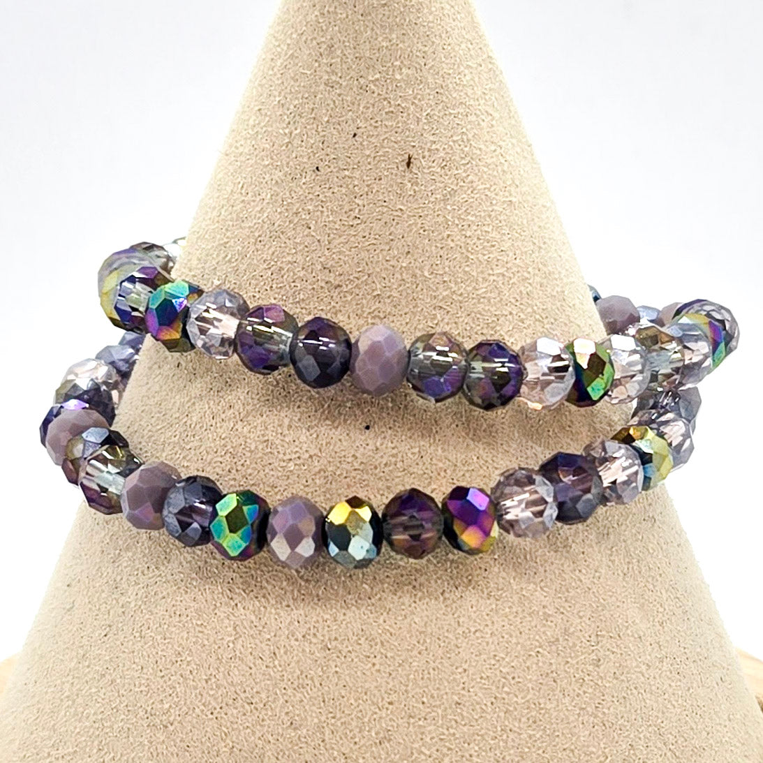 beaded bracelet in shades of purple on a tan jewelry display